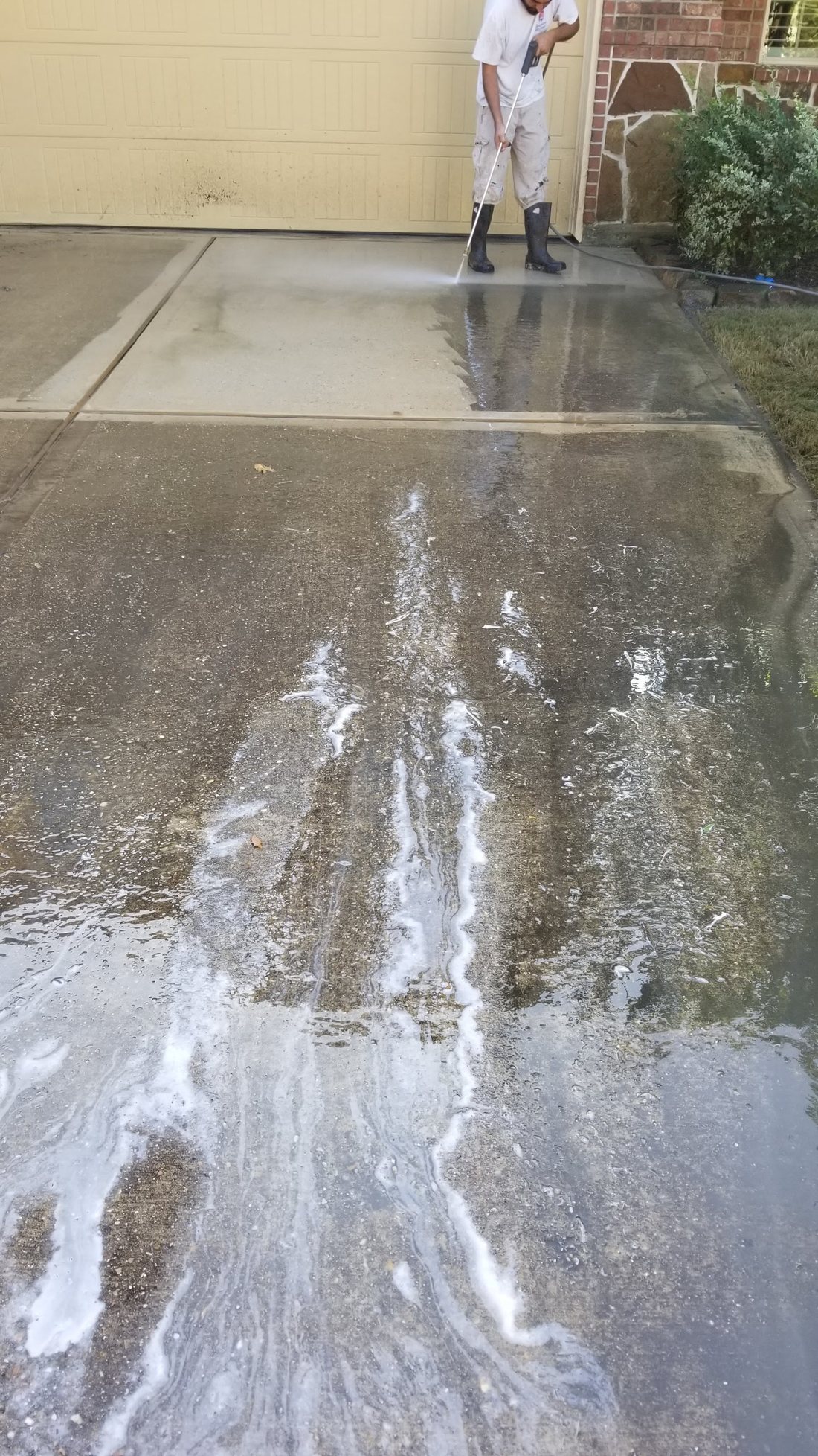 Off The Wall technician pressure washing a residential driveway